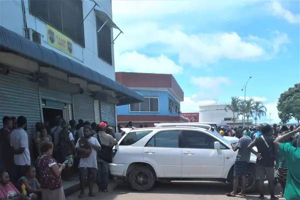 Curious onlookers yesterday outside the shop where the body of the Chinese shop owner was discovered.