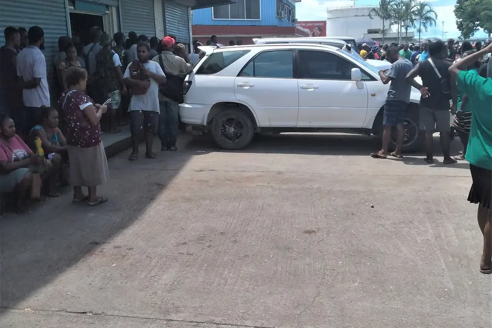 Curious onlookers yesterday outside the shop where the body of the Chinese shop owner was discovered.
