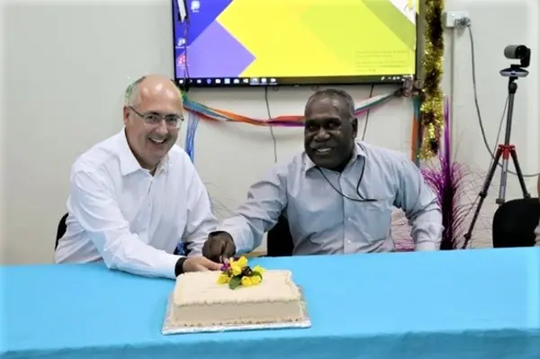 Dr Lachlan Strahan and Auditor General Peter Lokay celebrate by cutting a cake.