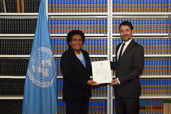 Solomon Islands’ flag; Ambassador Jane Kabui Waetara, Permanent Representative of Solomon Islands to the United Nations, depositing the Instrument of Ratification and David Nanopoulos, Chief of the Treaty Section of the UN Office of Legal Affairs.