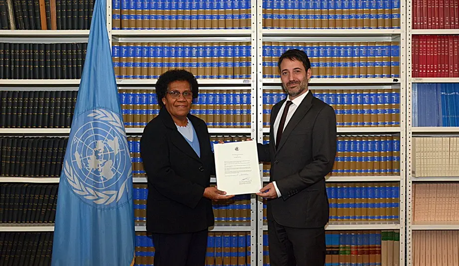 Solomon Islands’ flag; Ambassador Jane Kabui Waetara, Permanent Representative of Solomon Islands to the United Nations, depositing the Instrument of Ratification and David Nanopoulos, Chief of the Treaty Section of the UN Office of Legal Affairs.