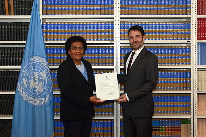 Solomon Islands’ flag; Ambassador Jane Kabui Waetara, Permanent Representative of Solomon Islands to the United Nations, depositing the Instrument of Ratification and David Nanopoulos, Chief of the Treaty Section of the UN Office of Legal Affairs.