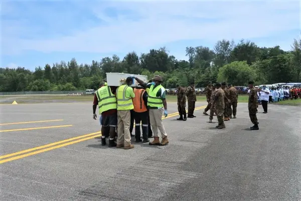 Casket being sprayed at Momote airport before being released.