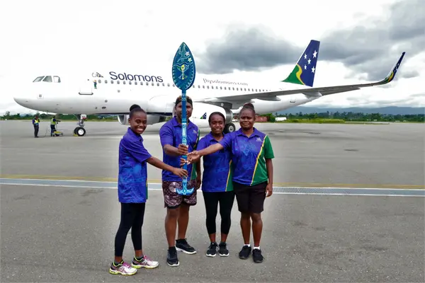 Solomon Airlines staff proudly holding up the Pacific Games Baton as it prepares to travel around the Solomon Islands.