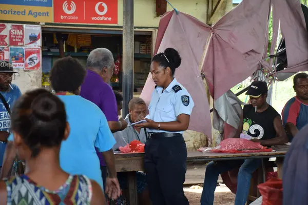 PC Luciana Binuika  explaining the police awareness pamphlets to an elder at Kukukm Market.