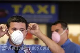 Airport workers put on surgical masks as they prepare to receive tourists arriving from Mexico at the Juan Santamaria International airport near San Jose, Monday, April 27, 2009.