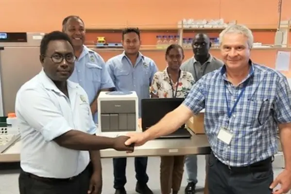 Front – MHMS Dr Gregory Jilini receiving the GeneXpert Machine and the laptop from WHO, Dr. Magdi Kassem with a handshake. Witnessing the handover were the Director of National Public Health laboratory, Mr. Dickson Manongi, Mr. Oliver Lukos (Medical Lab Technologist) and WHO staff; Ms Lanique Pitasua and Mr. Robinson Minevaleke at the back.