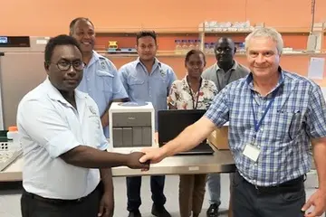 Front – MHMS Dr Gregory Jilini receiving the GeneXpert Machine and the laptop from WHO, Dr. Magdi Kassem with a handshake. Witnessing the handover were the Director of National Public Health laboratory, Mr. Dickson Manongi, Mr. Oliver Lukos (Medical Lab Technologist) and WHO staff; Ms Lanique Pitasua and Mr. Robinson Minevaleke at the back.