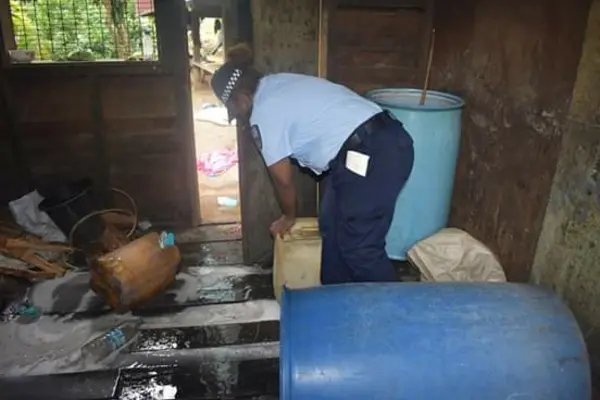 A female officer with the containers of kwaso during the raid.
