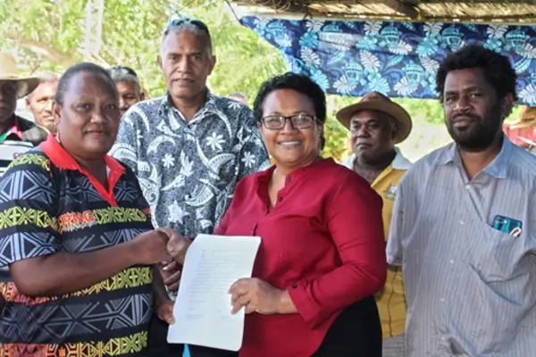 Wendy Saki Besa’a, a cassava out-grower got her signed agreement from MAL PS, Ethel Francis as Sape Farm Managing Director, Dr. Paul Bosawai Popora (right) and Undersecretary Technical Michael Ho’ota (from back row) looks on.