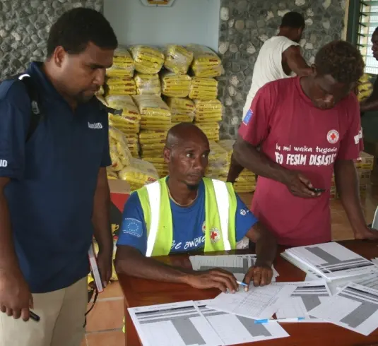 AusAID's rapid response officer, Eric Lui (L) and local authorities working out food distribution in Temotu Province.