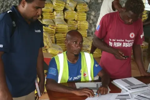AusAID's rapid response officer, Eric Lui (L) and local authorities working out food distribution in Temotu Province.