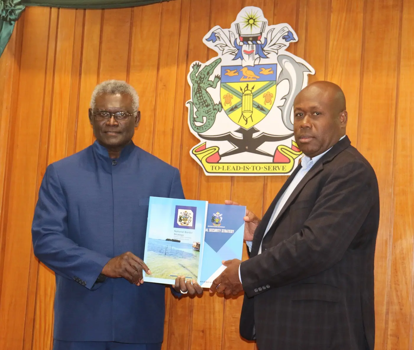 Minister for Police, National Security and Correctional Services Hon. Anthony Veke hands over the security strategy documents to the Prime Minister.