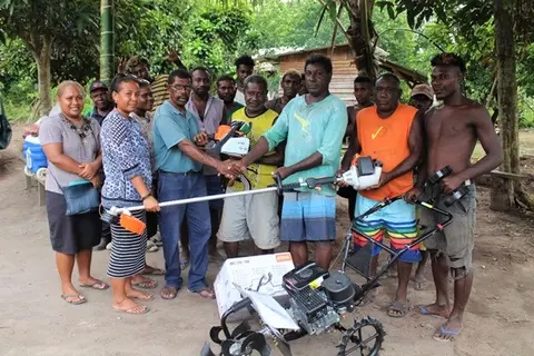 Daniel Ogu Besa’a, Minister of Agriculture & Fisheries of Guadalcanal Province (in green shirt) with two female officers from MAL Guadalcanal Province Extension Office hands over the tools to MK Farm Fresh owner and recipient John Maeli  Kauvera, flanked by his farm workers.