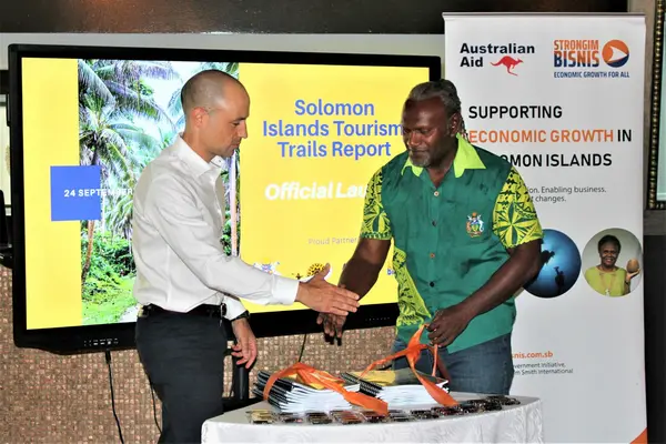 MCT Permanent Secretary Andrew Honiara shaking hands with Australian High Commission Counsellor for Economics Andrew Schloeffel, after untying ribbons to officially launch the report.