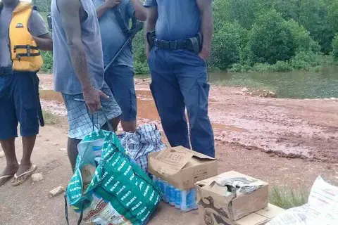 Officers at Atori and community member display some of seized cartons of alcohol