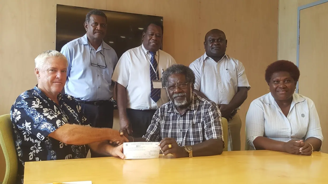 Chairman, SINPF Board, Mr Boyers, handing over a cheque of $120 million to Minister of Finance & Treasury, Hon Rini, in the presence of Ruth Alepio, SINPF Board Secretary (sitting). At the back, standing from left: General Manager (Acting) SINPF, Mike Wate, Governor CBSI, Denton Rarawa and Permanent Secretary Ministry of Finance, Harry Kuma.