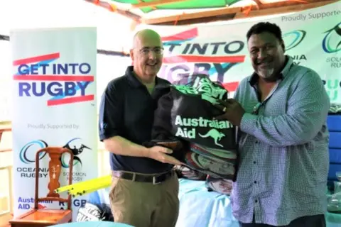 Australian High Commissioner Dr Lachlan Strahan handing over equipment to Solomon Island Rugby Union Federation President George Tema.