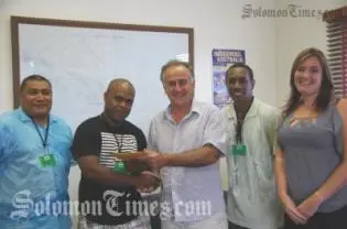 Jeddy Dyer receives his ticket and schedule from the Australian High Commissioner, H.E Frank Ingruber.