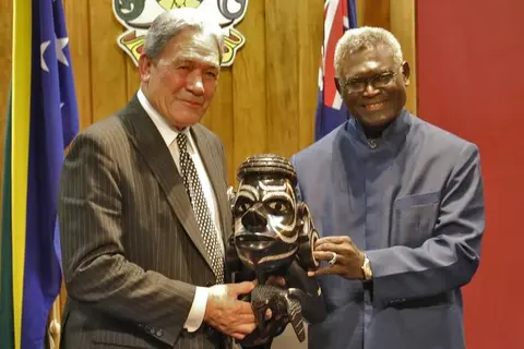 Solomon Islands Prime Minister Manasseh Sogavare presents a Nguzu Nguzu to New Zealand's Deputy Prime Minister Winston Peters.