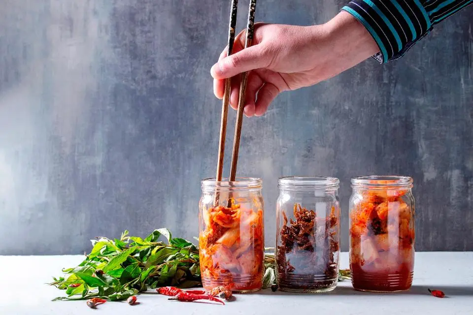 Korean traditional fermented appetizer kimchi cabbage and radish salad, fish snack served in glass jars.