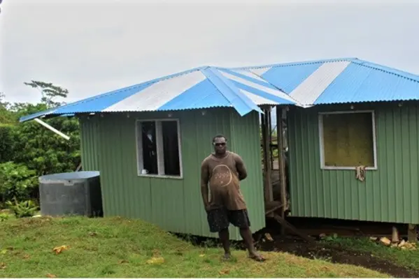 Eddie Voko in-front of his new permanent home that he build through money acquired from shallot sales. The home is in construction phase and is nearing completion.