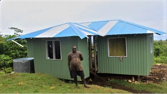 Eddie Voko in-front of his new permanent home that he build through money acquired from shallot sales. The home is in construction phase and is nearing completion.