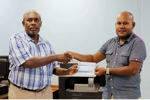 Central Guadalcanal Constituency Officer, Mr. Philip Naisa hands over the cheques to Constituency School fee Coordinator Joe Frazer.