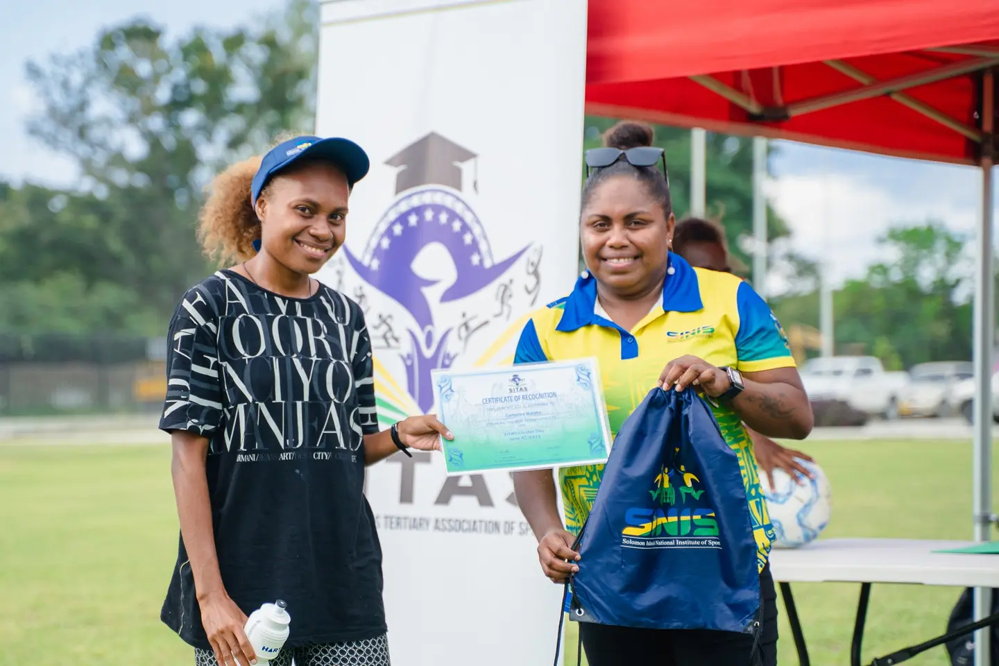 Ms. Catherine Mateka of GS Faisi Rural Training Centre being awarded with the SINIS certificate of ‘Athlete of the Cluster Day’ by SINIS People and Partnership Coordinator Joyce Aburii.