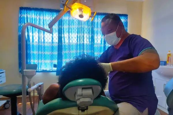 Dentist Dr William Hatingongo attending to a patient with the donated dental chair and equipment.