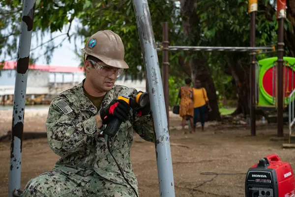 Logistics Specialist 3rd Class Steven Athas, from San Diego, sands down paint from a swing set during a renovation project at the Rove Children’s Park during Pacific Partnership 2022.