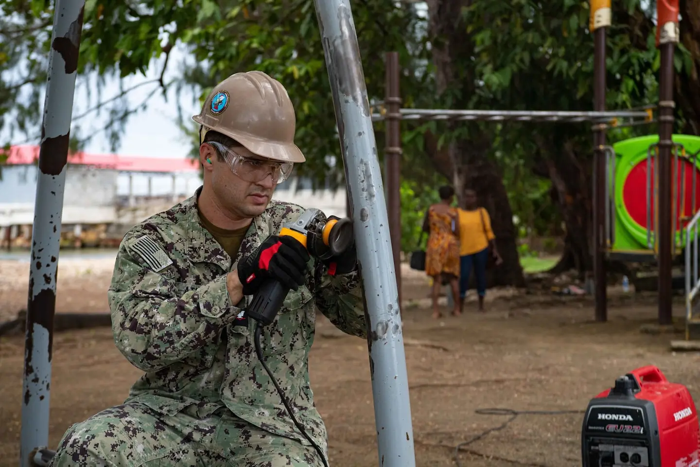 Logistics Specialist 3rd Class Steven Athas, from San Diego, sands down paint from a swing set during a renovation project at the Rove Children’s Park during Pacific Partnership 2022.