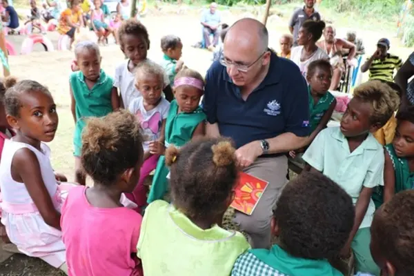 Australian High Commissioner Dr Lachlan Strahan reads gifted books to children at Papagu Early Childhood Development Centre.
