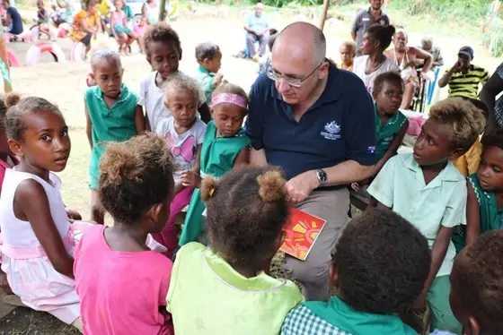Australian High Commissioner Dr Lachlan Strahan reads gifted books to children at Papagu Early Childhood Development Centre.