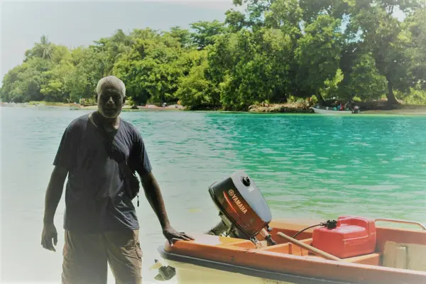Jesse standing beside his ray boat, behind him is Taro Island the capital of Choiseul Province.
