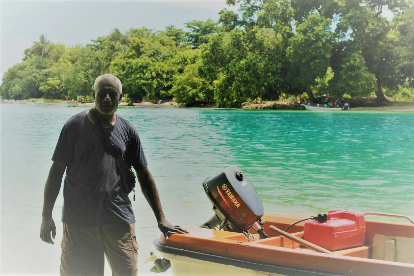 Jesse standing beside his ray boat, behind him is Taro Island the capital of Choiseul Province.
